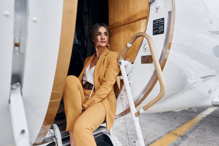 Woman in yellow clothes sits inside of private airplaneの写真素材