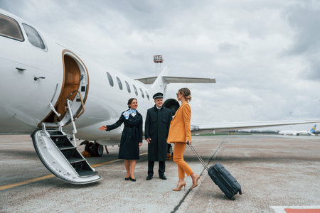 A young woman in yellow clothes is accompanied by an airline workersの写真素材