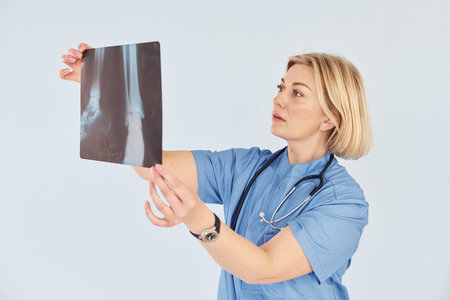 Holds x-ray. Middle-aged professional female doctor in uniform and with stethoscopeの写真素材