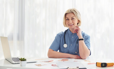 In the cabinet. Middle-aged professional female doctor in uniform and with stethoscopeの写真素材
