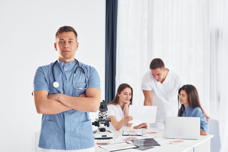 Man standing and posing. Group of young doctors is working together in the modern office