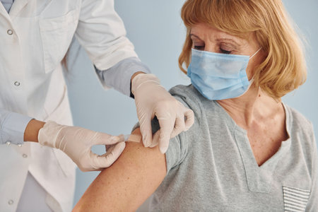Young female doctor giving injection to senior woman at hospitalの写真素材