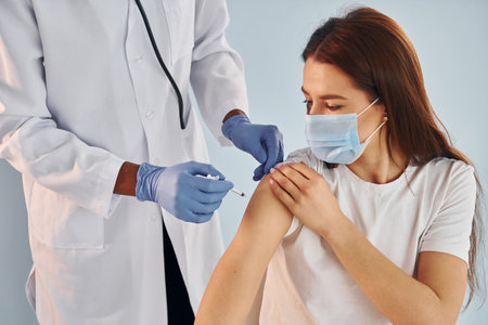 Young african american doctor giving injection to woman at hospitalの写真素材