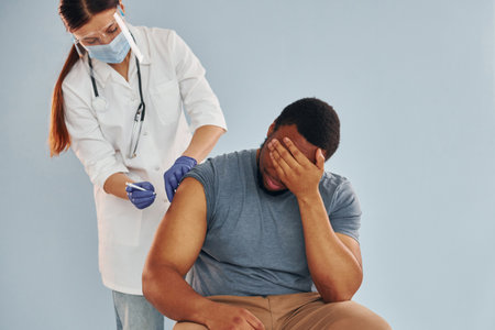 Female doctor giving injection to african american man at hospitalの写真素材