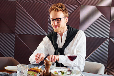 Man in glasses sits by the table. Indoors of new modern luxury restaurantの写真素材