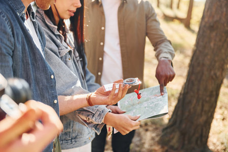 Holding map and looking for location. Group of young people is traveling together in the forestの写真素材
