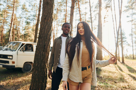 Bus is behind. Young couple is traveling in the forest at daytime togetherの写真素材