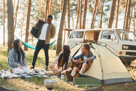 Camp and car. Group of young people is traveling together in the forest at daytimeの写真素材
