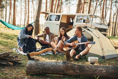 Camp and car. Group of young people is traveling together in the forest at daytimeの写真素材