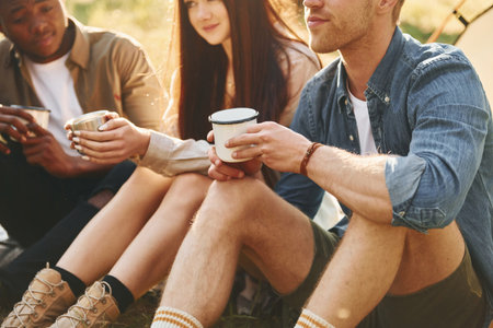 Talking with each other. Group of young people is traveling together in the forest at daytimeの写真素材