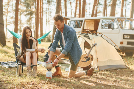 Having a rest. Young couple is traveling in the forest at daytime togetherの写真素材