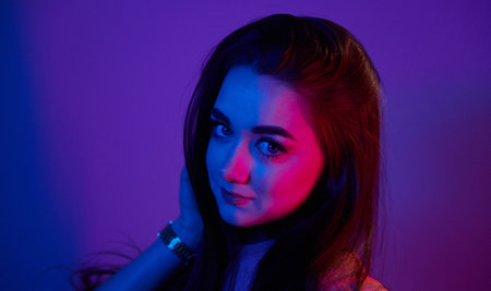 Portrait of fashionable young woman that standing in the studio with neon lightの写真素材