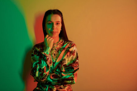 Posing for camera. Fashionable young woman standing in the studio with neon lightの写真素材