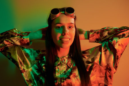 Retro eyewear. Fashionable young woman standing in the studio with neon lightの写真素材