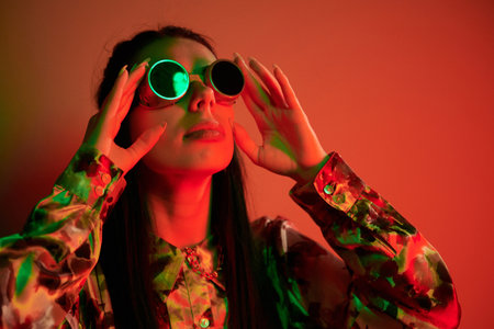 Looks to the side. Fashionable young woman standing in the studio with neon lightの写真素材