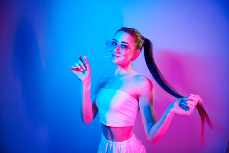 Positive emotions. Fashionable young woman standing in the studio with neon lightの写真素材