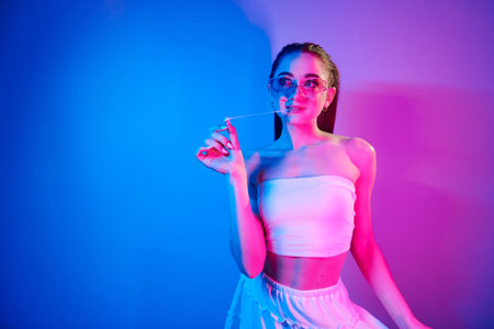 Positive emotions. Fashionable young woman standing in the studio with neon lightの写真素材