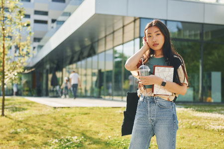Standing on the grass. Young asian woman is outdoors at daytimeの写真素材