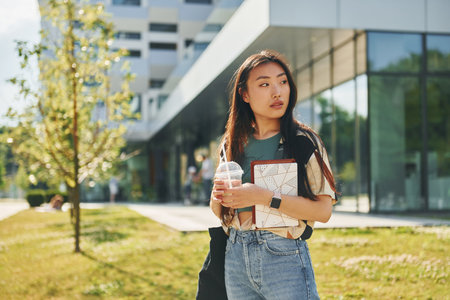 Standing on the grass. Young asian woman is outdoors at daytimeの写真素材