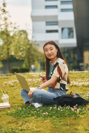 Conception of education. Young asian woman is outdoors at daytimeの写真素材
