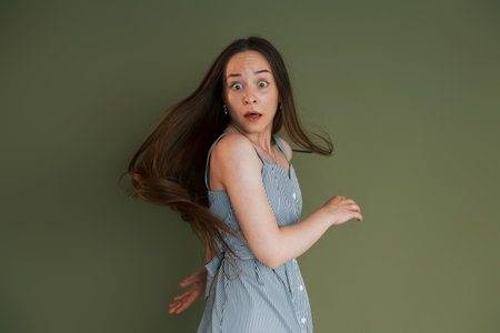 Scared young woman in casual clothes standing indoors in the studioの写真素材