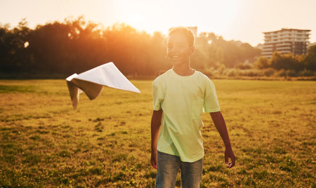 With paper plane. African american kid have fun in the field at summer daytimeの写真素材