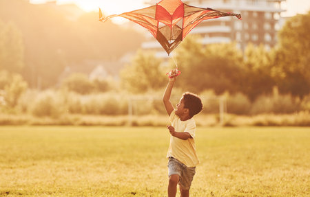 Red kite. African american kid have fun in the field at summer daytimeの写真素材
