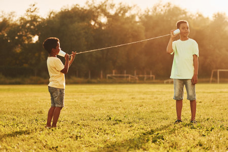 Old toy phone. Two african american kids have fun in the field at summer daytime togetherの写真素材