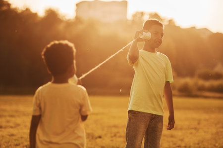 Old toy phone. Two african american kids have fun in the field at summer daytime togetherの写真素材
