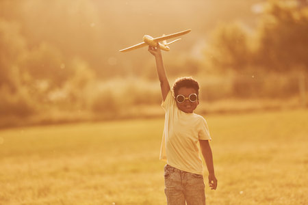 Power of imagination. Playing pilot game. African american kid have fun in the field at summer daytimeの写真素材