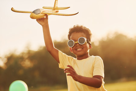 Power of imagination. Playing pilot game. African american kid have fun in the field at summer daytimeの写真素材