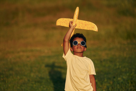 With pilot sunglasses. African american kid have fun in the field at summer daytimeの写真素材