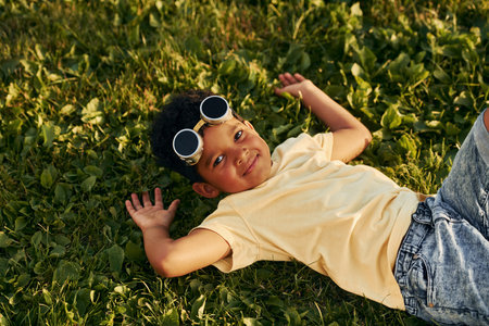 Lying down on the grass. African american kid have fun in the field at summer daytimeの写真素材