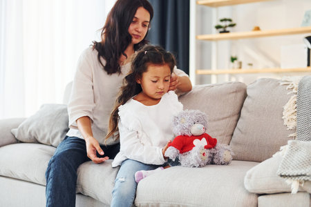 Sitting on the sofa. Mother and her daughter spending time together at homeの写真素材