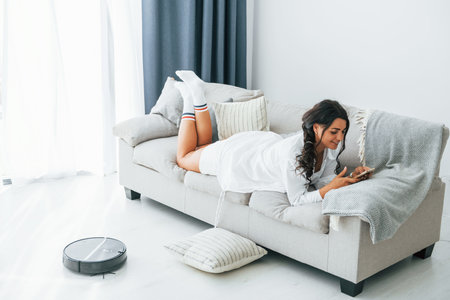 Having weekend. Woman in casual clothes is indoors at homeの写真素材