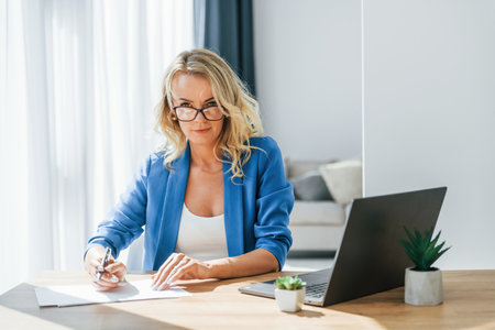 Busy business days. Woman in casual clothes is indoors at homeの写真素材