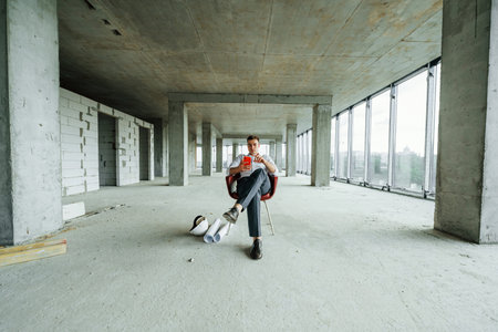 Successful young man in formal wear is working indoors on the construction