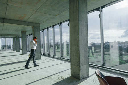 Successful young man in formal wear is working indoors on the constructionの写真素材