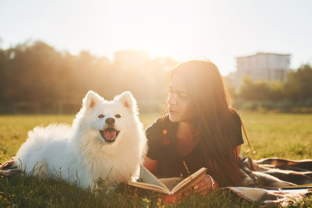 Woman with her dog is having fun on the field at sunny daytime. Beautiful sunshineの写真素材