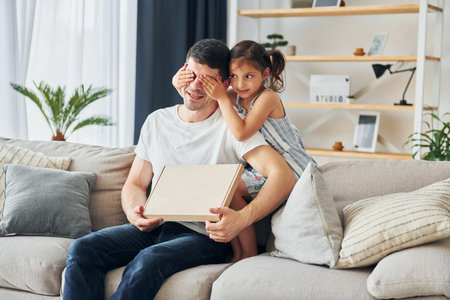 Father in casual clothes is indoors at home with his daughterの写真素材