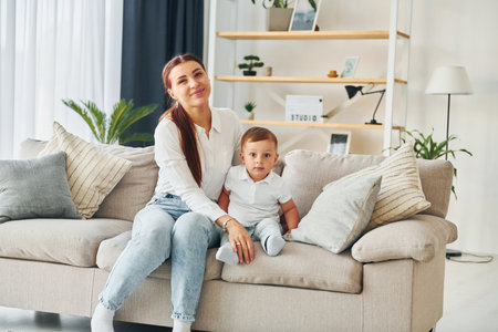Woman sits together with her son on the sofa at homeの写真素材