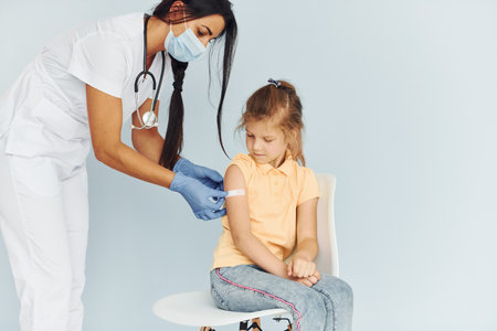 Doctor in uniform making vaccination to the little girlの写真素材