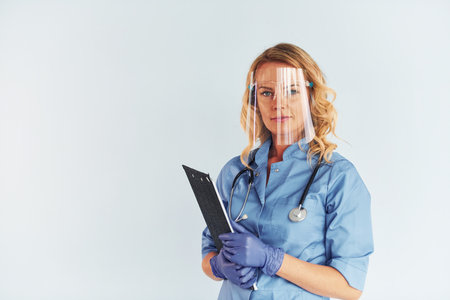 Wearing protective mask. Young female doctor in uniform is indoorsの写真素材