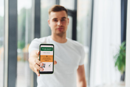 Young man in white shirt is indoors against white backgroundの写真素材