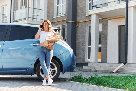 With products. Young woman in casual clothes with her electromobile outdoors at daytimeの写真素材