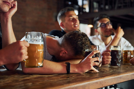 Side view of friends with beer. People in casual clothes sitting in the pubの写真素材