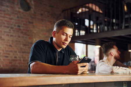 Beautiful interior. Man in casual clothes sitting in the pubの写真素材