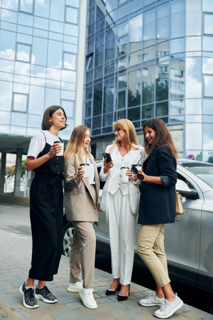 Women in formal wear is outdoors in the city together standing near silver colored carの写真素材