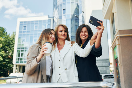 Positive women in formal wear is outdoors in the city togetherの写真素材