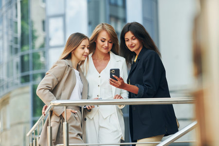 Using phone. Women in formal wear is outdoors in the city togetherの写真素材